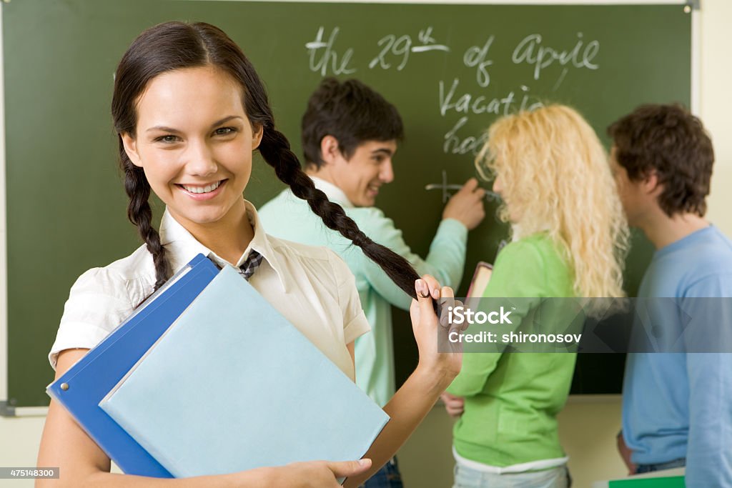 Cheerful student Portrait of cute girl holding textbook in hands on background of communicating students   Note to inspector: the image is pre-Sept 1 2009 2015 Stock Photo