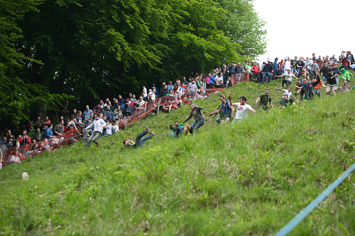 Brockworth, England - May 25, 2015: Entrants chasing the cheese at the 2015 ‘Cheese Rolling’ held at Cooper’s Hill, in the Cotswolds.