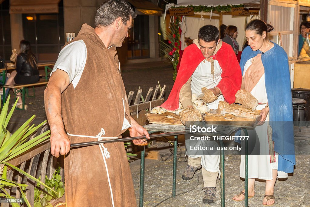 Roman baking bread in the street market Braga, Portugal - May, 20th 2015: Roman street traders baking bread in the street. Tourists in the background. This roman festival depicting the period where romans named the city of Braga, Bracara Augusta its original roman name by César Augusto. 2015 Stock Photo