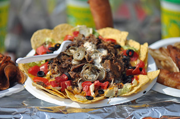 Mexican nachos with sour cream, black olives, ground beef, black beans, tomatoes, shredded cheese, jalapenos, rice, and cilantro