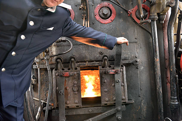 Firebox of a steam locomotive St. Petersburg, Russia - May 7, 2015: Machinist assistant opens the firebox of a steam locomotive. The parade of steam locomotives dedicated to the WWII Victory Day firebox steam engine part stock pictures, royalty-free photos & images
