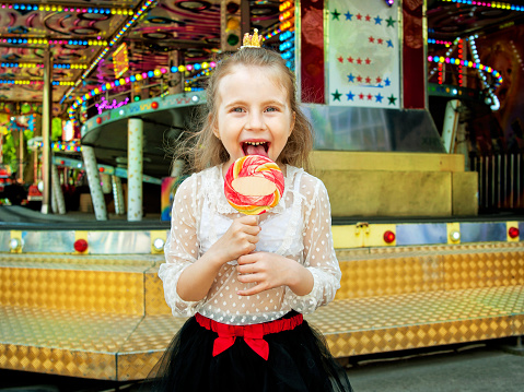 cute little girl with lollipop at amusement park