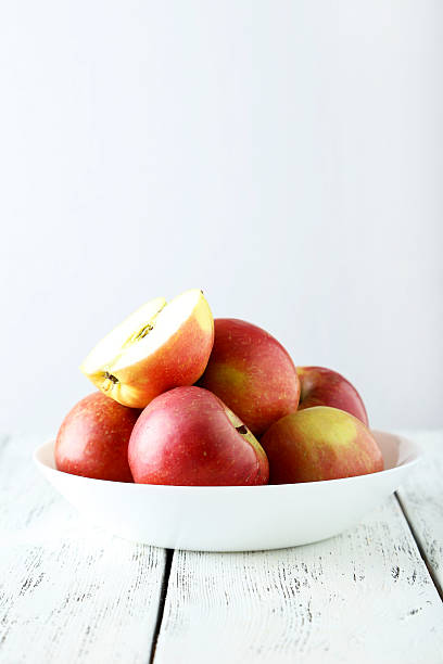 istock Apples in bowl on white wooden background 475155492