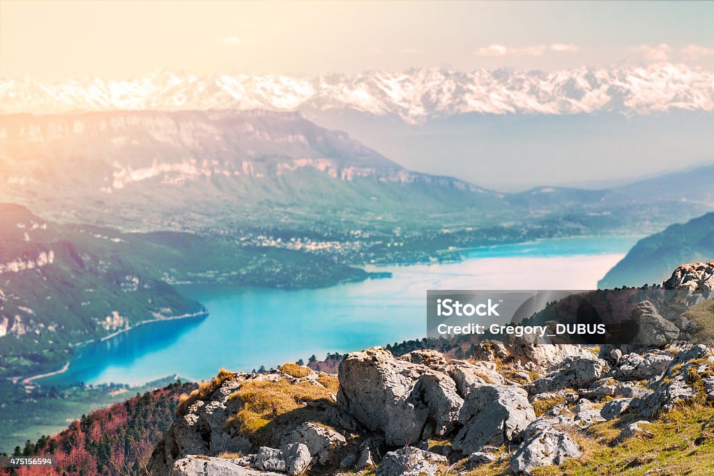 Bourget lake and Mont Blanc massif Alps mountain scenics view Horizontal scenics landscape view of Bourget lake with Aix les Bains city (in Savoie) in background, and Mont Blanc massif, from top mountain peak, of Alps chain in end of summer, autumn season. Photography taken on Grand Colombier mountain (near Culoz city), in Bugey, in Ain, Rhone-alpes region in France (Europe). Selective focus on rocks on foreground and blurred background. Aix-Les Bains Stock Photo