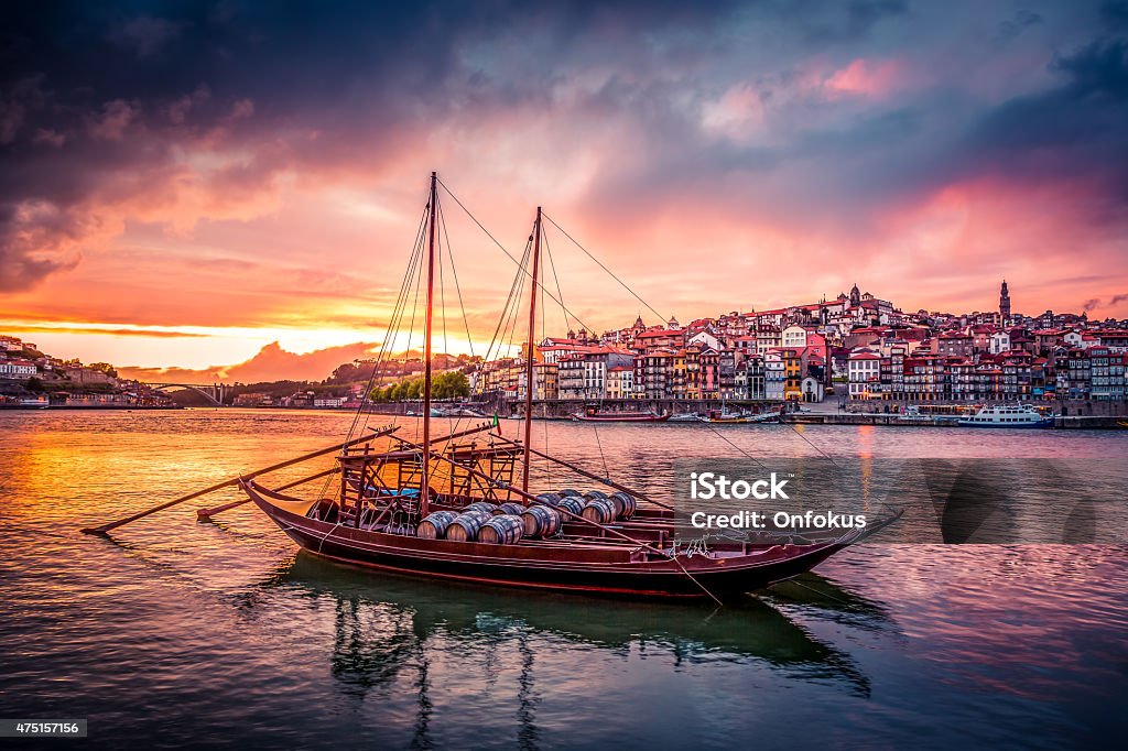 Porto at Sunset with Rabelo Boats on Douro River Porto at Sunset with Rabelo Boats on Douro River and the city in the background. The sky is coloured and the boats are in the foreground. Porto - Portugal Stock Photo