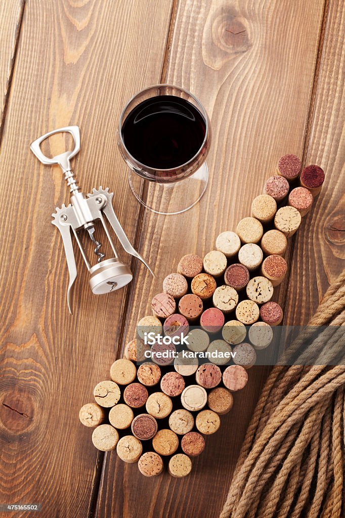 Wine bottle shaped corks, glass of red wine and corkscrew Wine bottle shaped corks, glass of red wine and corkscrew over rustic wooden table background. Top view 2015 Stock Photo