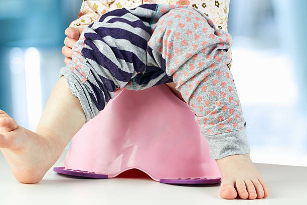 istock Children's legs hanging down from a chamber-pot on a green 475165994