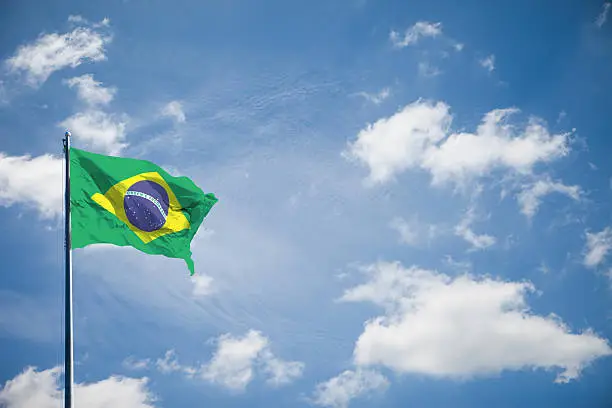 Federative Republic of Brazil flag is waving on blue sky background