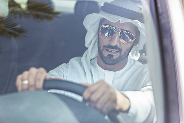 Emirati man driving his car Middle Eastern man driving his car, he's wearing the typical Emirati dishdasha. arabian sunglasses stock pictures, royalty-free photos & images