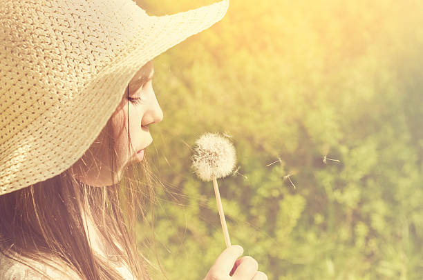 istock Little girl blowing a dandelion 475171278