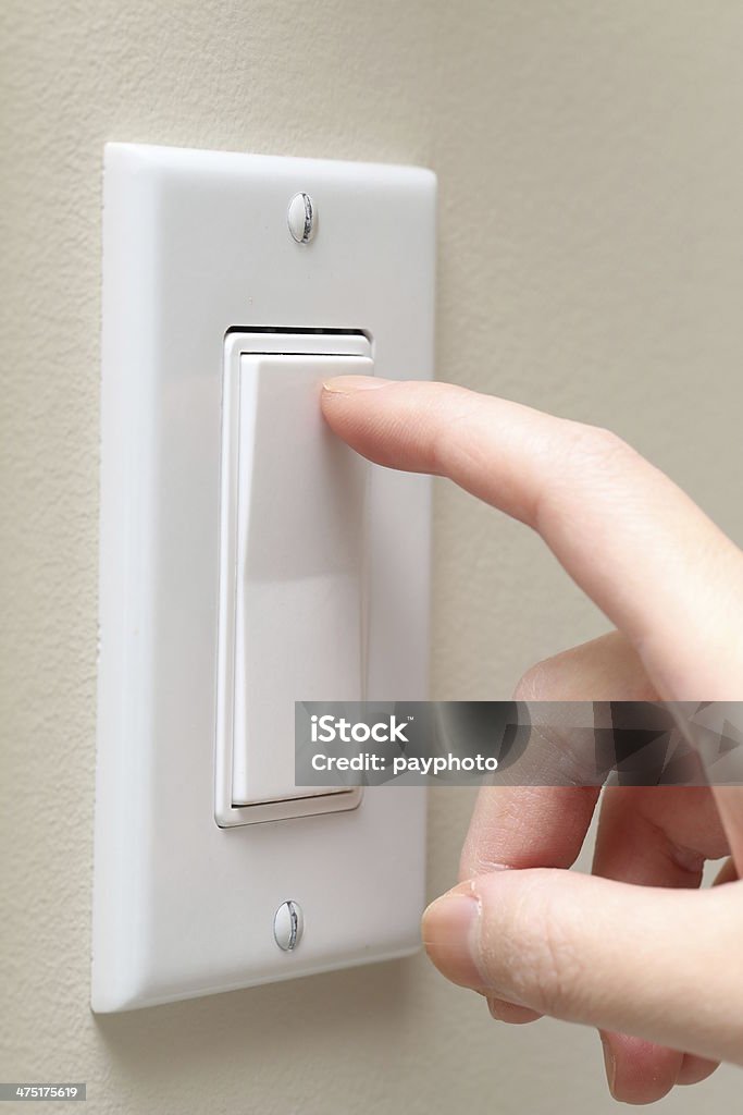 Turning light on / off Woman hand turning on the light with a wall switch Light Switch Stock Photo