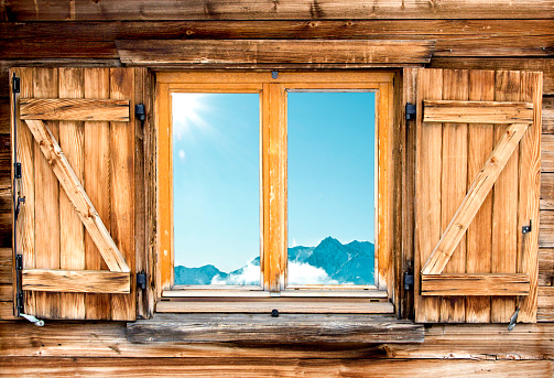 Weathered facade of a mountain hut with mountain  reflection in the window