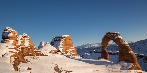 Wide angle view of Delicate Arch covered in snow in Winter at Arches National Park in Utah