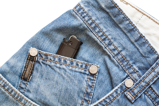 Blue denim background and cigarette lighter in pocket isolated on white background