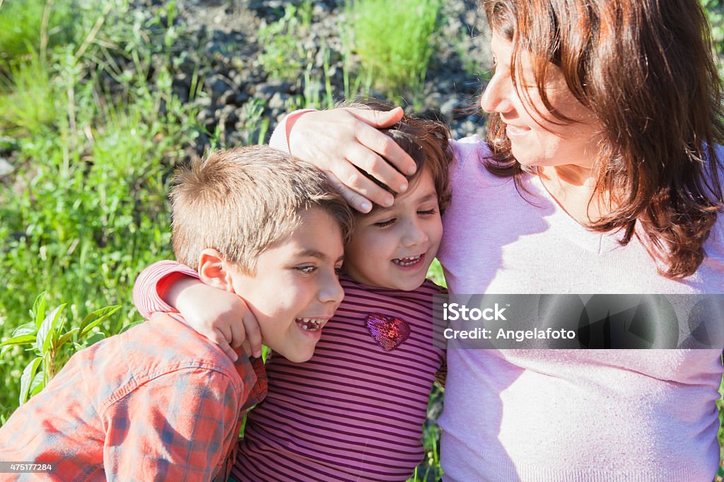 Mother Embracing Her Son and Daughter mother Embracing Her Son and Daughter, outdoors at sunset 2015 Stock Photo