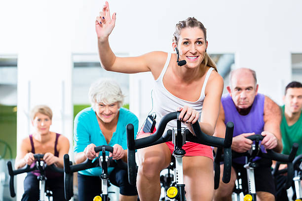 senior personnes dans la salle de sport du centre de remis'en forme de vélo de spinning - spinning instructor exercising gym photos et images de collection