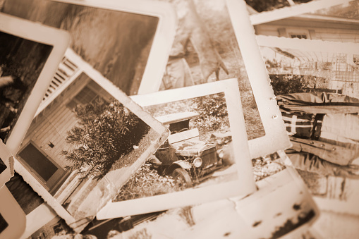 Many vintage, sepia-toned photographs from the 1940s lying in a large pile.  Old-fashioned memories from the past.  Antiques.  No people in this toned image and any people in the photos are unrecognizable.  Photos are of home lifestyles, vehicle in the 1940s.
