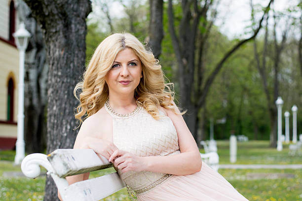 istock Blond woman in evening gown sitting on white bench 475181876