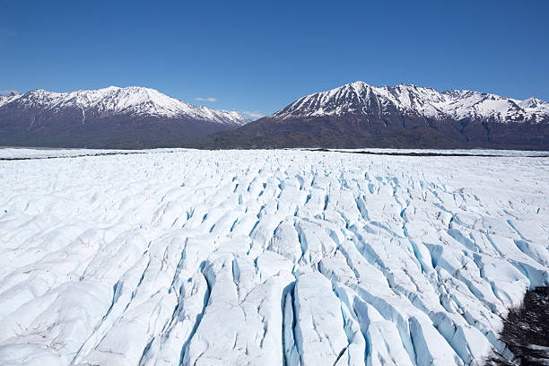 The Knik River and its glacier are starting to thaw and break apart.  The ice is a blue color, with the Alaska Mountain Range seen in the background.  The Matanuska Mountains, valley and Matanuska Glacier are featured.