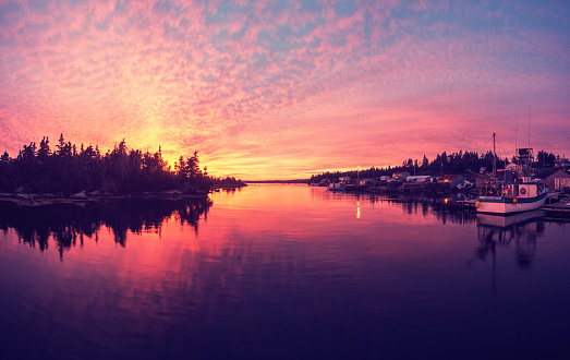 A vibrant sunset bathes a tiny fishing village in colour on Nova Scotia's Eastern Shore.  Panoramic view, stitched images.