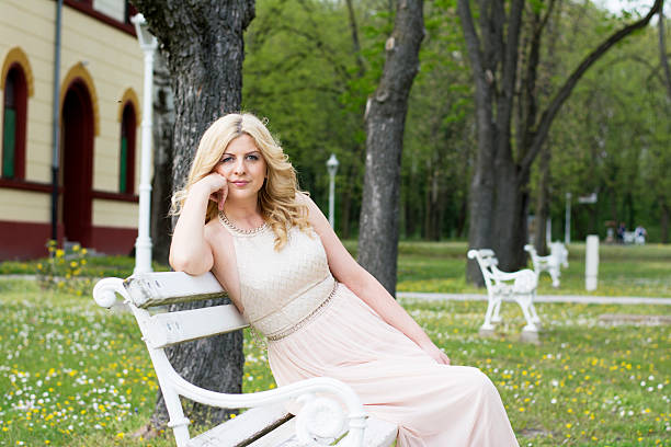 istock Blond woman in evening gown sitting on white bench 475187806