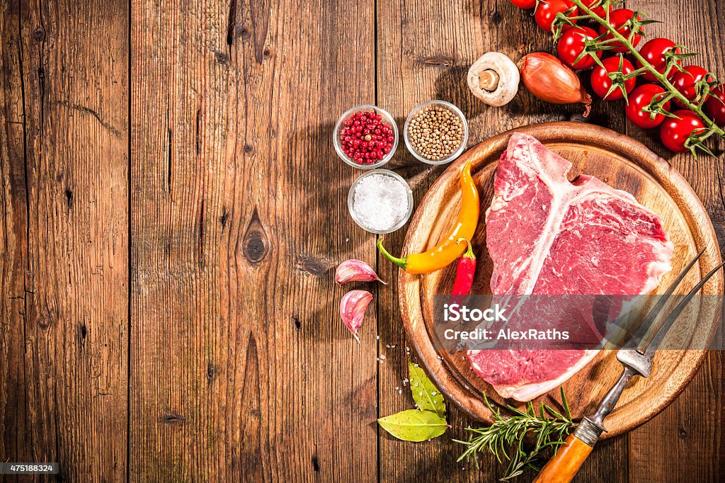 Raw fresh meat t-bone steak Raw fresh meat t-bone steak and seasoning on wooden background 2015 Stock Photo