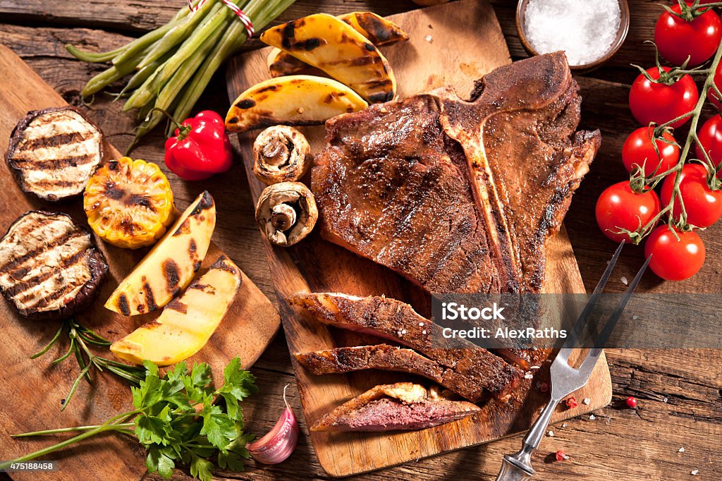 Beef steaks with grilled vegetables Beef steaks with grilled vegetables and seasoning on wooden background 2015 Stock Photo