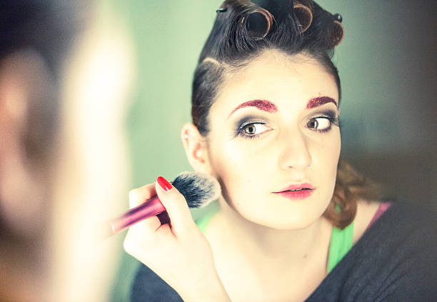 istock Young woman looking at herself in a mirror applying make-up 475190709