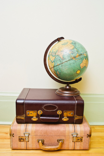 Vintage suitcases piled on top of one another with a globe on top