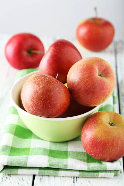 istock Apples in bowl on white wooden background 475195320