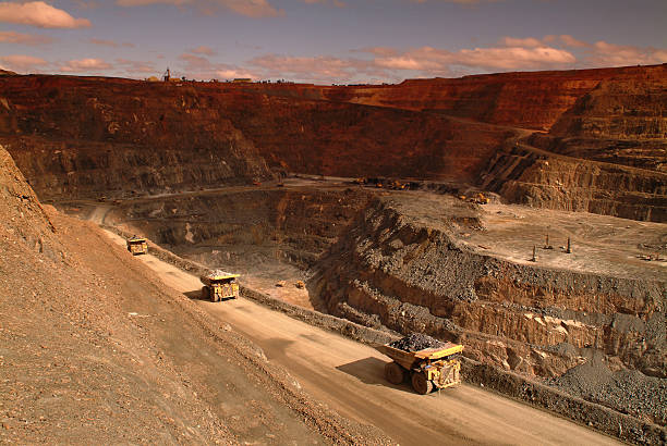 istock Several haul trucks carrying ore in an open cut mine. 475196393