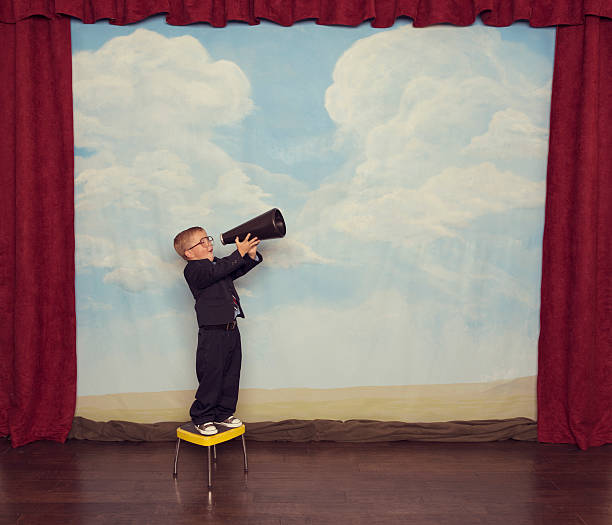 istock Young Boy Salesman Yells Through Megaphone on Stage 475201823