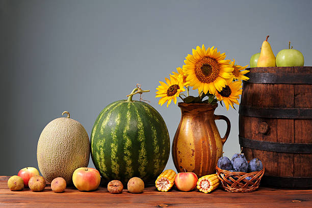 Fruits, vegetables and sunflowers in a vase on the table