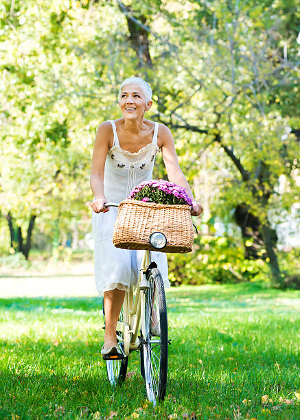 istock Elderly woman riding a bicycle in a park 475203087