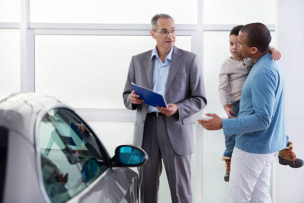 アフリカ系アメリカ人の父と息子には、車のセールスマンについて説明します。 - car african descent shopping car dealership ストックフォトと画像