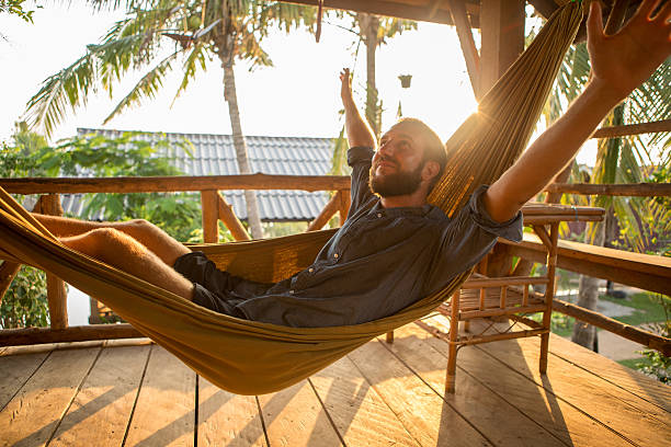 istock Happy young man relaxing on hammock at sunset 475205624