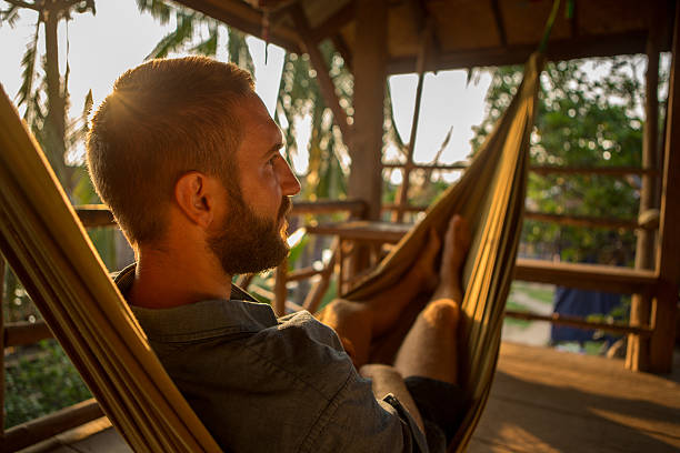 istock Young beard man relaxing on hammock at sunset 475205628