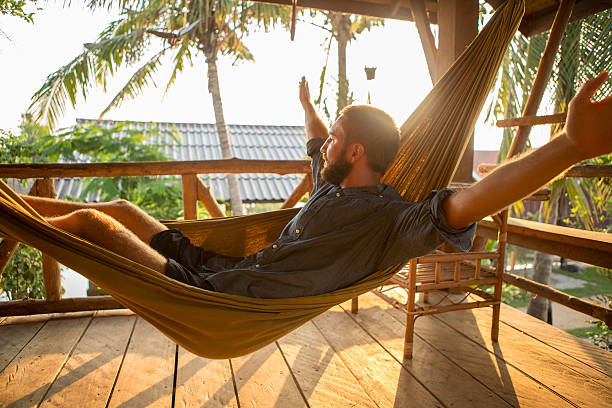 istock Carefree man relaxing on hammock at sunset 475205630