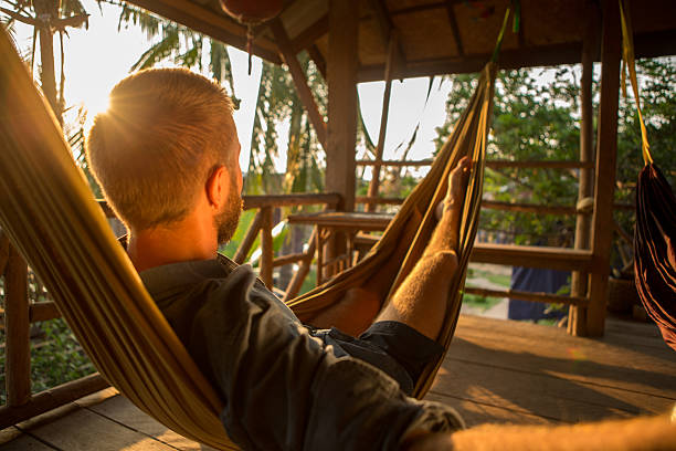 istock Young man on a hammock at sunset relaxing 475205632