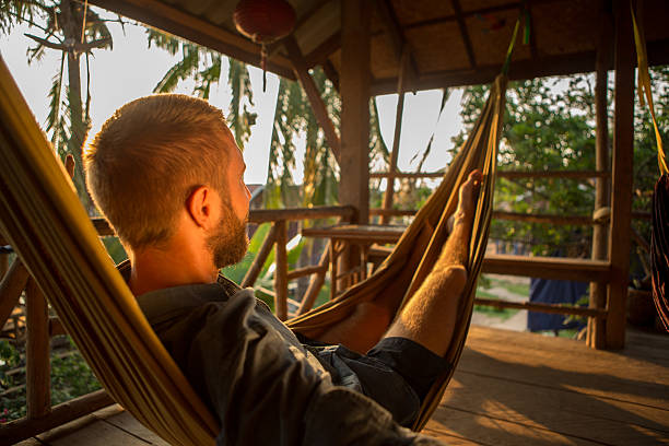 istock Young man on hammock at sunset enjoying relaxing time 475205636