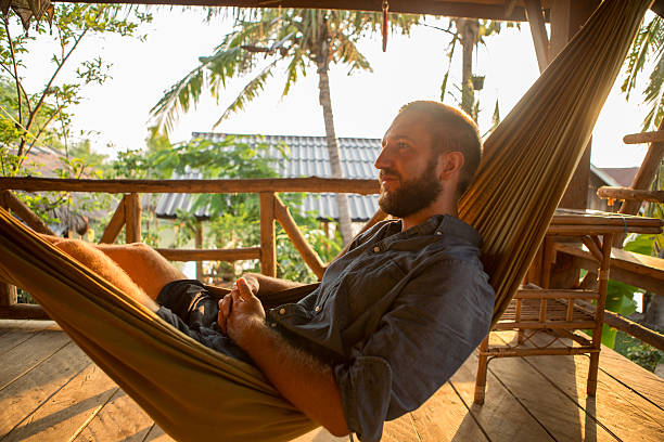istock Young man relaxing on hammock at sunset 475205638