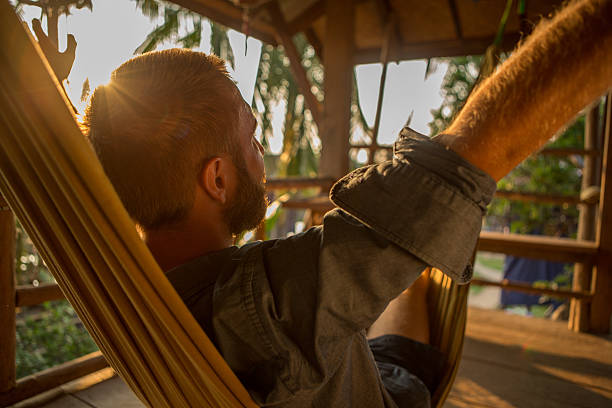 istock Man on hammock at sunset stretching arms for positive emotion 475205646
