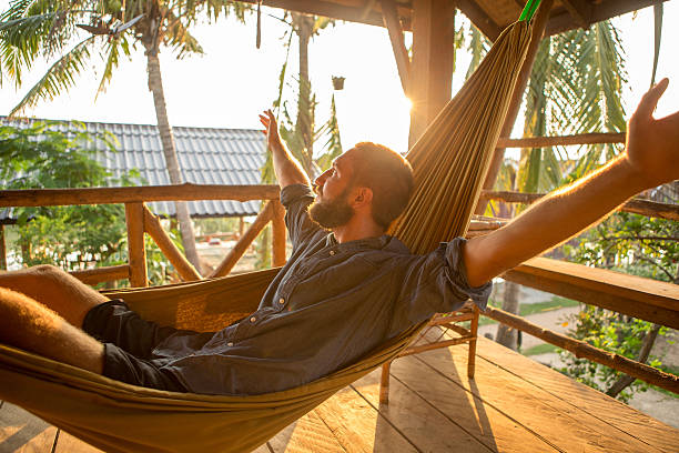 istock Man on hammock at sunset arms outstretched for freedom 475205648