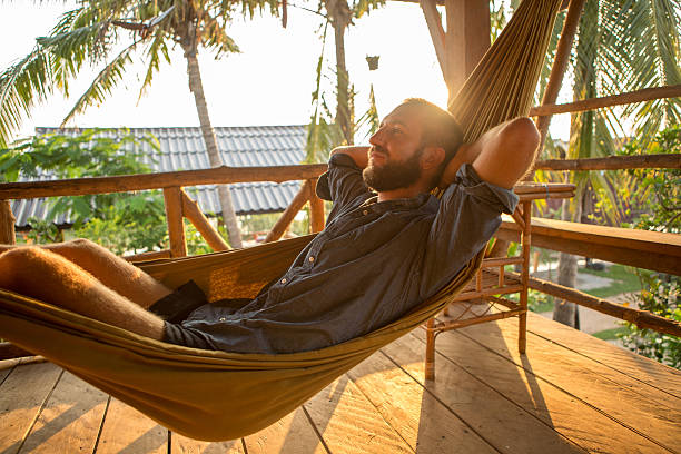 istock Cheerful man relaxing on hammock at sunset 475205650