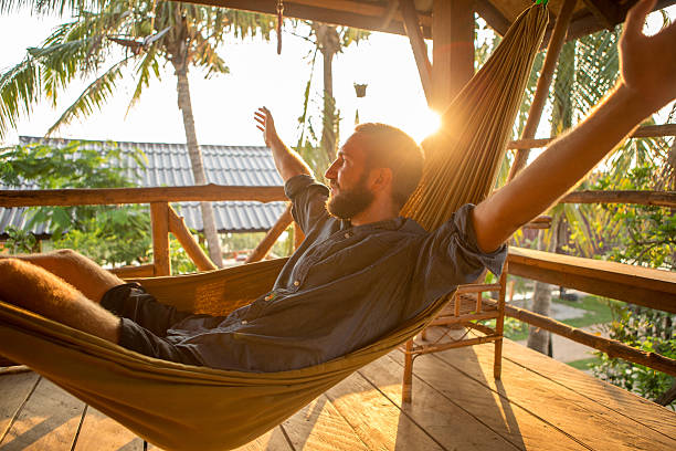 istock Carefree young man relaxing on hammock at sunset 475205652