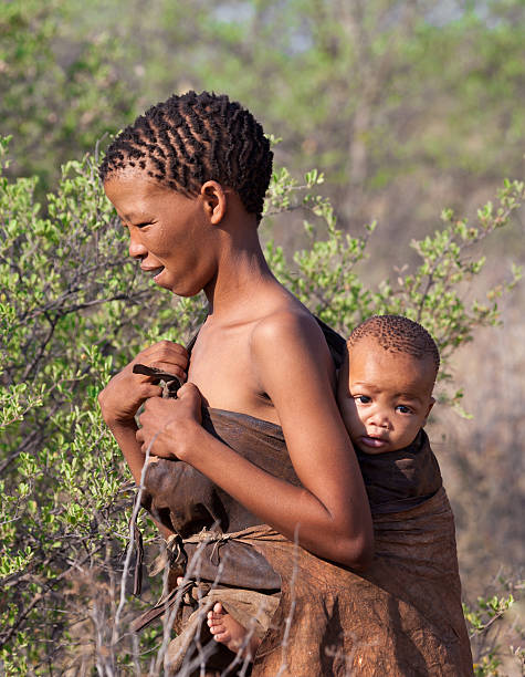 Portrate of Bushman woman with childe in Botswana Kalahari Desert, Botswana-October 16, 2011. Young Bushman woman with child in natural their life environment in Kalahari Desert of Botswana. bushmen stock pictures, royalty-free photos & images