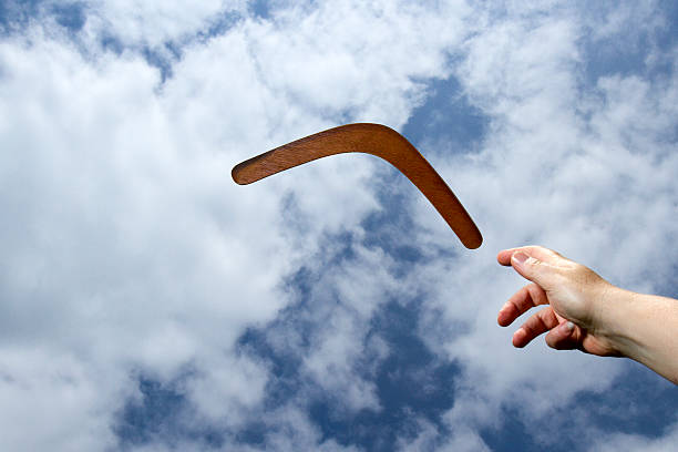 Throwing plain boomerand, midair Throwing a plain wooden boomerang midair with blue sky and cloud background. boomerang stock pictures, royalty-free photos & images