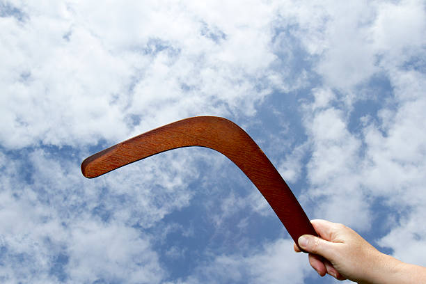 Throwing plain boomerang Wooden boomerangin hand with blue sky and cloud background. airfoil photos stock pictures, royalty-free photos & images