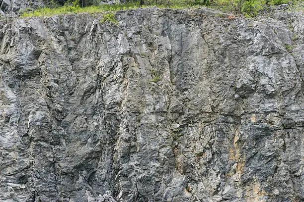 Weathered rock texture in old stone-pit with parts of green.