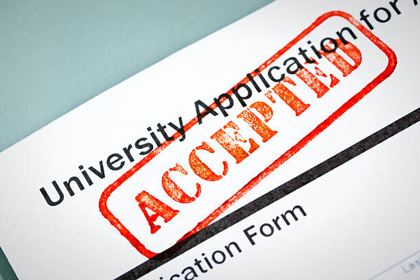 University Application Acceptance Notification Letter with ACCEPTED Stamp An acceptance letter from a university application. An university application form and the letter of acceptance with a red rubber stamp of "Accepted" on a table top still life. Photographed close-up in horizontal format with selected focus on the rubber stamp impression. college acceptance letter stock pictures, royalty-free photos & images